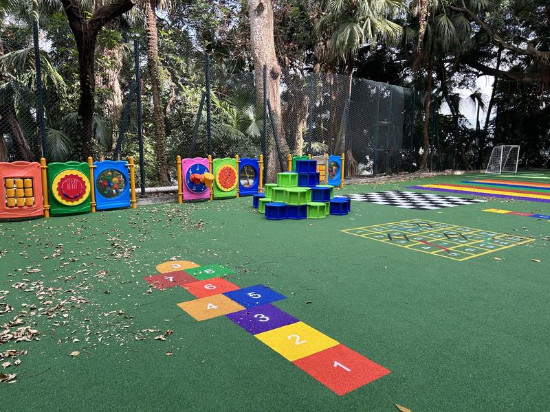 Green playground surface with colourful activity markings
